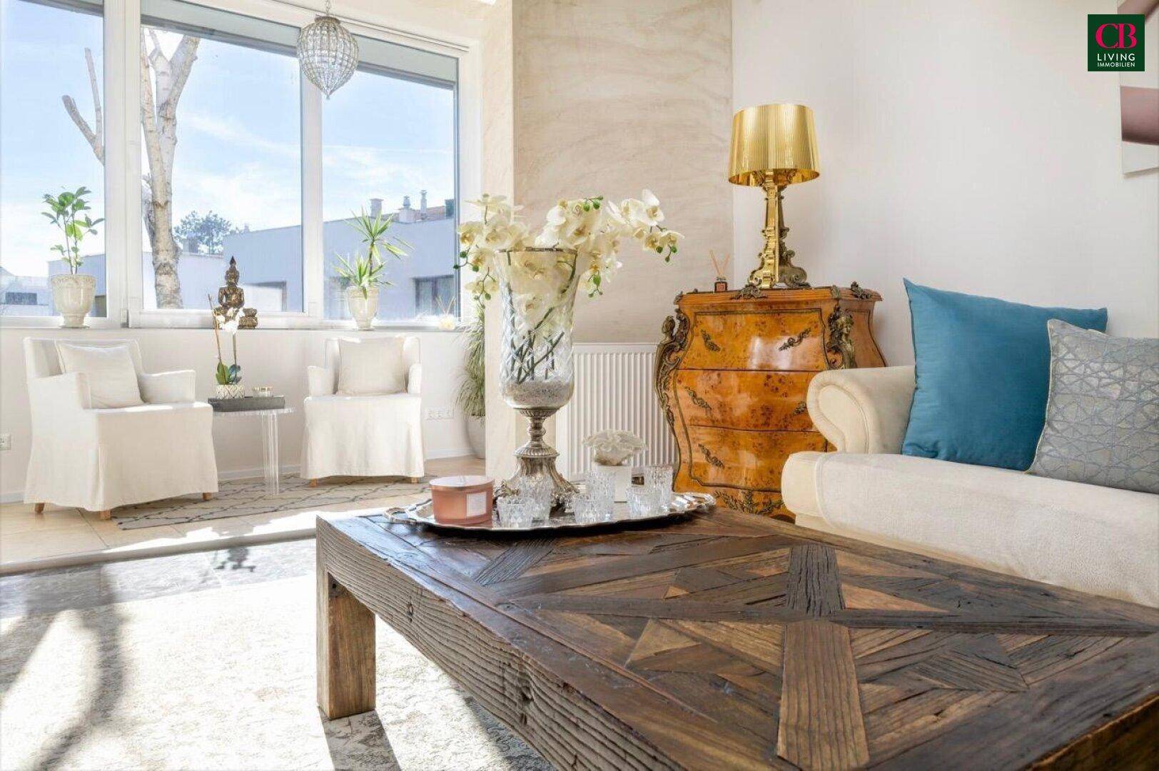 Gemütlicher Wohnbereich mit Holztisch, Blumenarrangement und Blick auf den sonnigen Außenbereich.