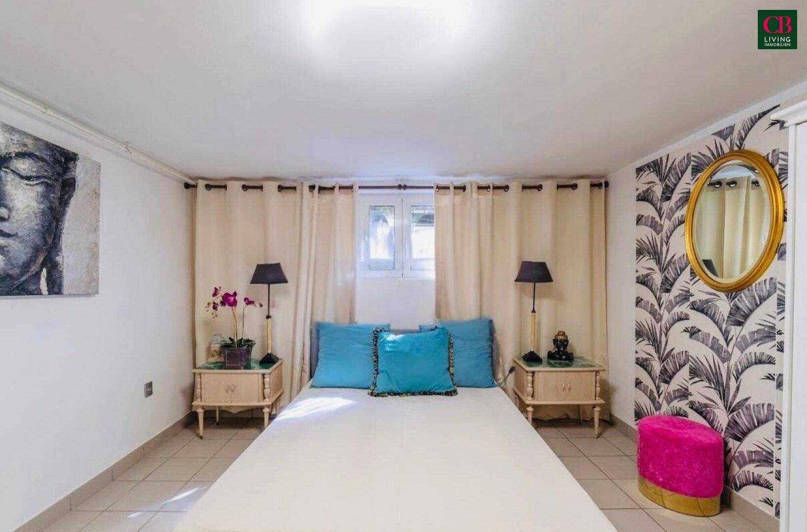 Schlafzimmer mit Fliesenboden, Doppelbett und auffälliger Tapete an einer Wand.