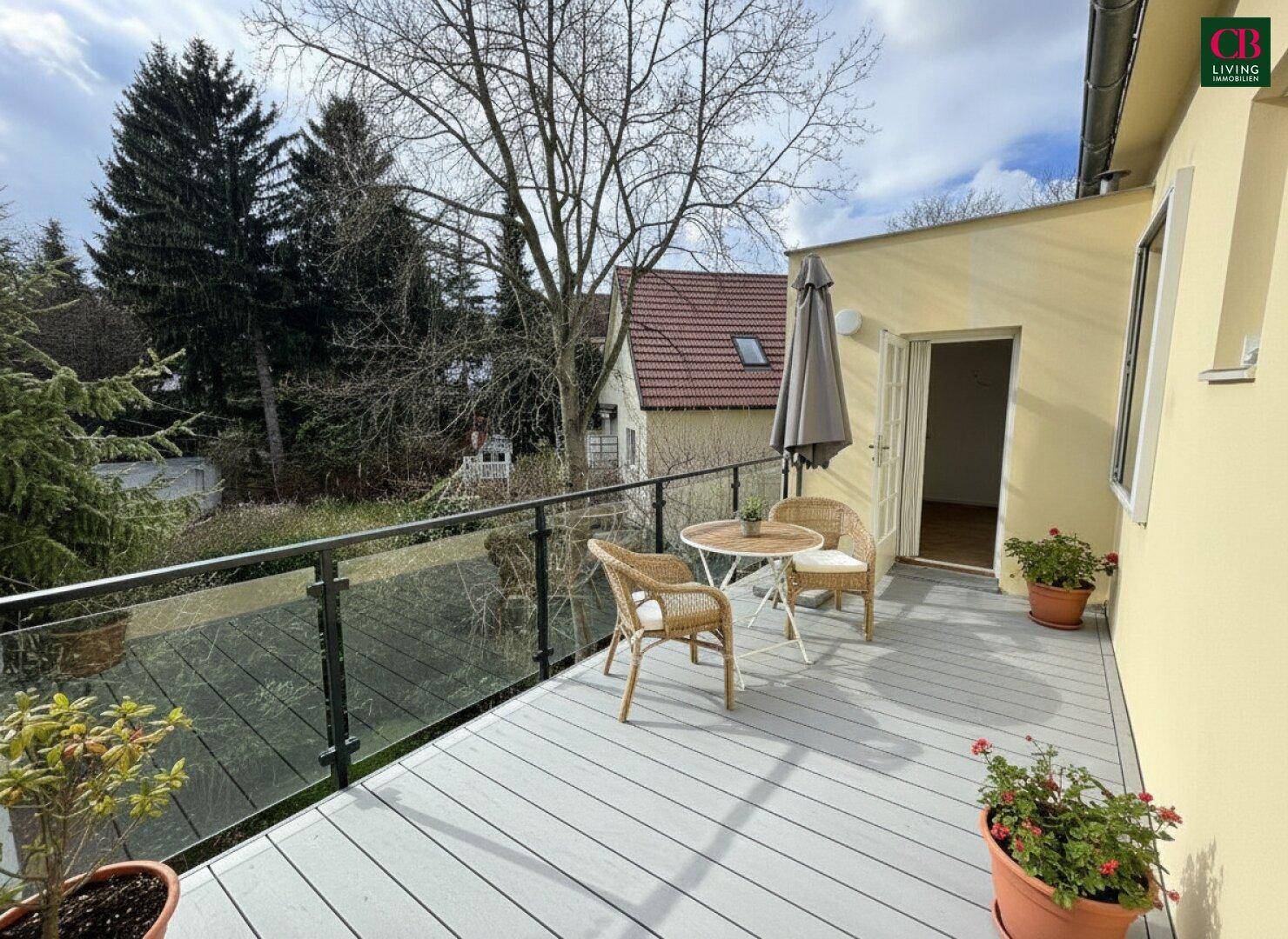 Renovierter Balkon mit modernem Glasgeländer, neuen Dielen und Sitzgelegenheiten.