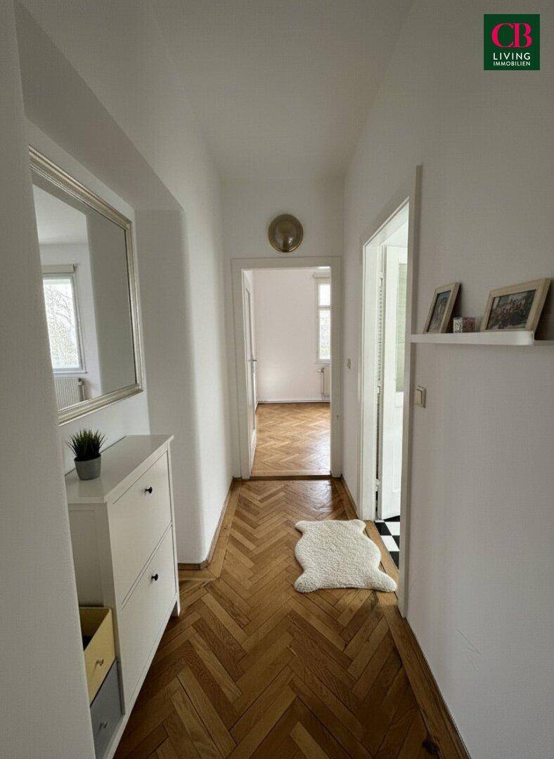 Heller Flur mit Fischgrätparkett, Spiegel und Schuhschrank, modern eingerichtet.