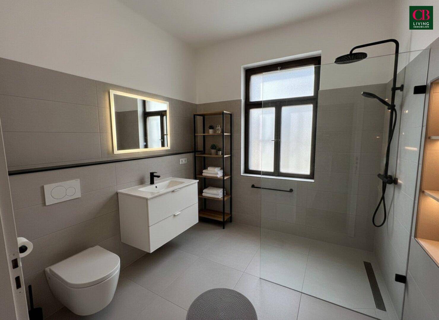 Modernes Badezimmer mit grauen Fliesen, begehbarer Dusche und schwebendem Waschtisch.