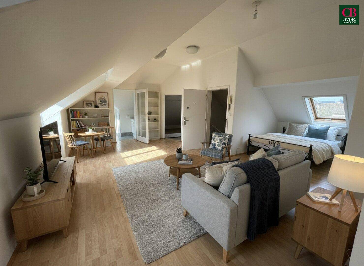 Helles Dachgeschoss-Wohnzimmer mit Holzboden, Dachschrägen, integriertem Schlafbereich und Essplatz.