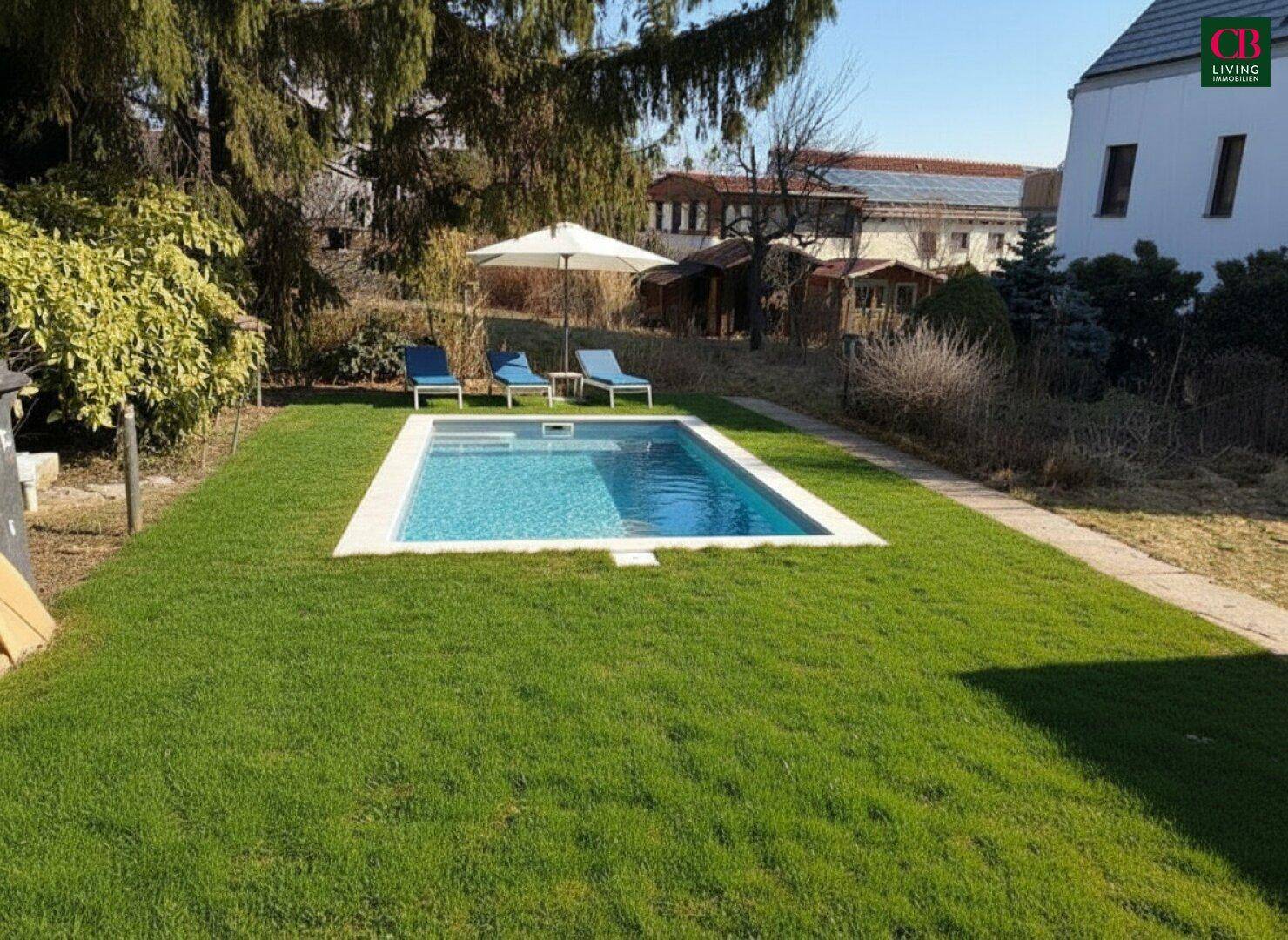 Gepflegter Garten mit eingelassenem Swimmingpool, umgeben von Rasen und Liegestühlen.