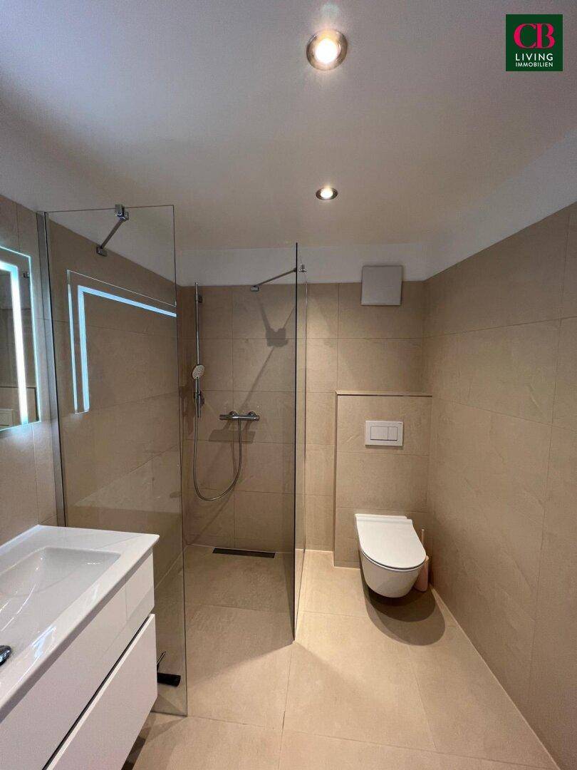 Modernes Badezimmer mit begehbarer Dusche, wandhängendem WC und beigefarbenen Fliesen.