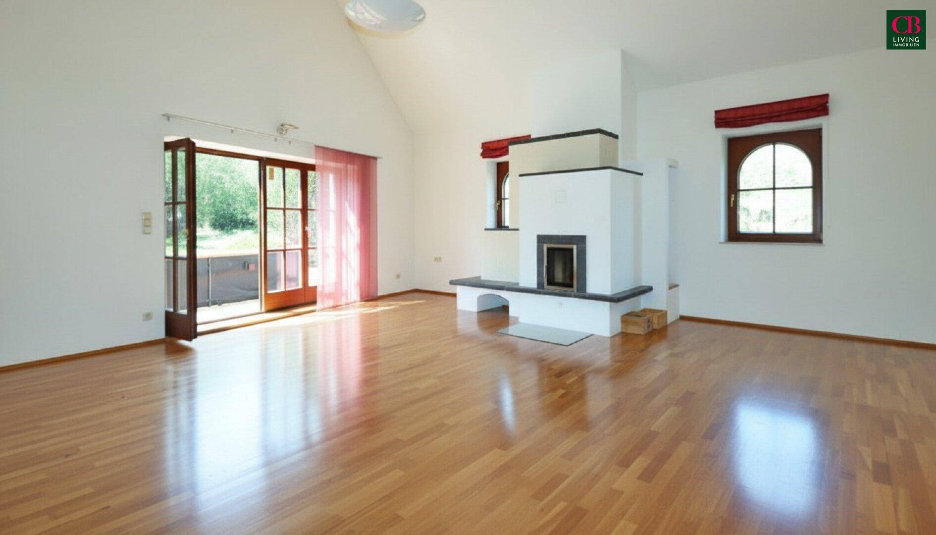 Helles Wohnzimmer mit Holzboden, Kamin und Zugang zum Garten durch große Terrassentüren.