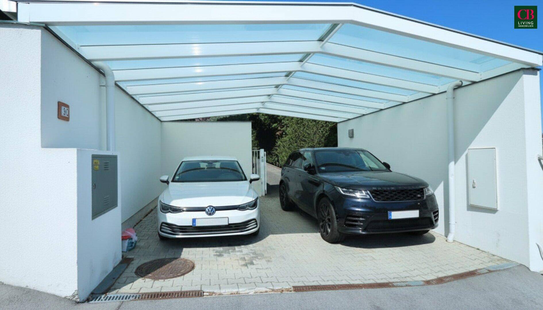 Überdachter Carport für zwei Fahrzeuge mit Glasdach und gepflastertem Boden.