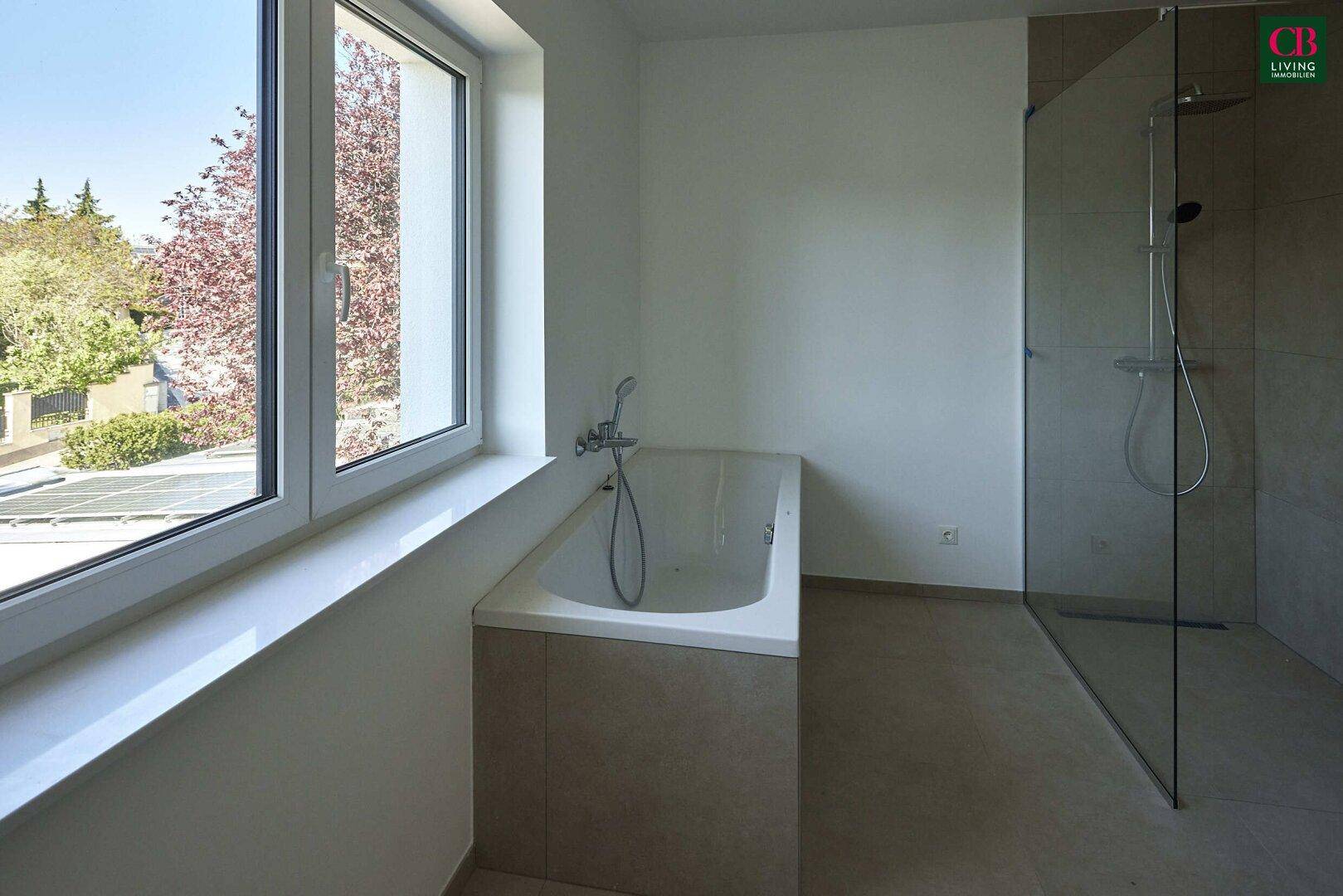 Modernes Badezimmer mit Badewanne unter dem Fenster und einer geräumigen begehbaren Dusche.