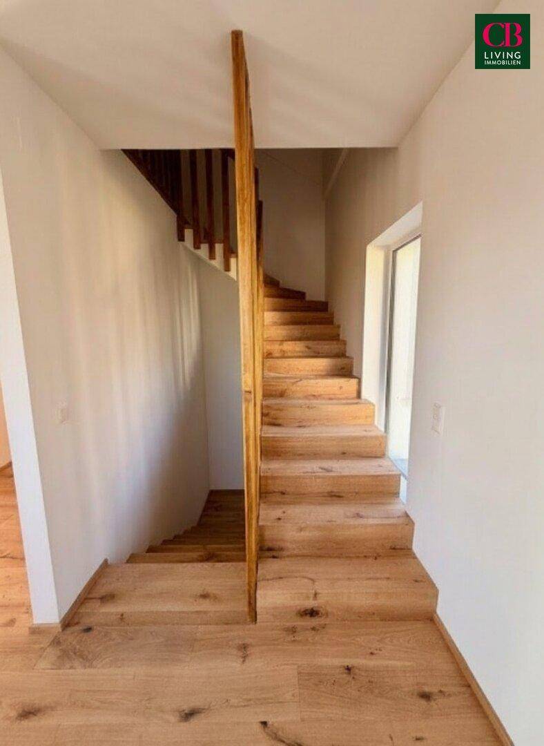 Helle Holztreppe mit schlichtem Geländer, die die verschiedenen Etagen des Hauses verbindet.