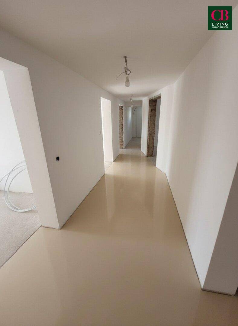 Moderner Flur mit glänzendem Bodenbelag und weißen Wänden, der zu weiteren Räumen führt.