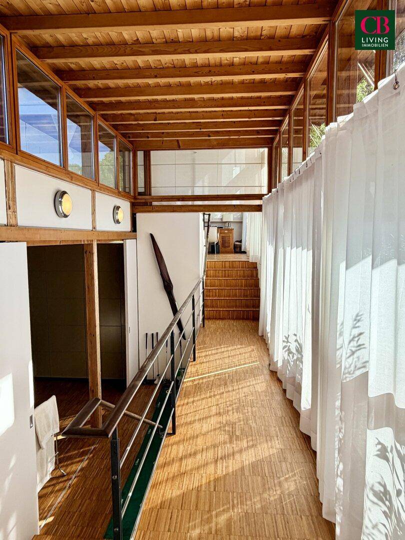 Heller Flur mit Holzboden und Holzdecke, der zu weiteren Räumen und einer Treppe führt.