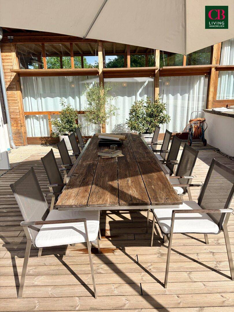 Detailansicht der Holzterrasse mit Esstisch und Stühlen, perfekt für entspannte Stunden im Freien.