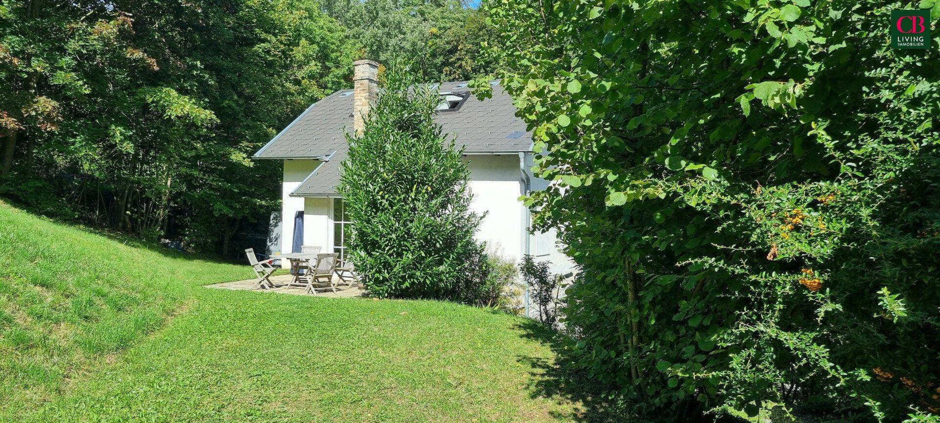 Idyllisches Einfamilienhaus mit großer Rasenfläche und gemütlicher Terrasse umgeben von viel Grün.