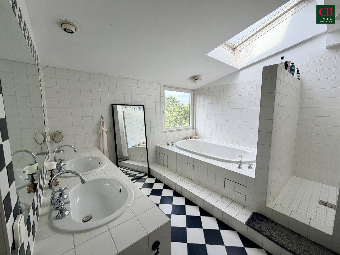 Geräumiges Badezimmer mit Doppelwaschbecken, Badewanne und Dusche, hell durch Dachfenster.