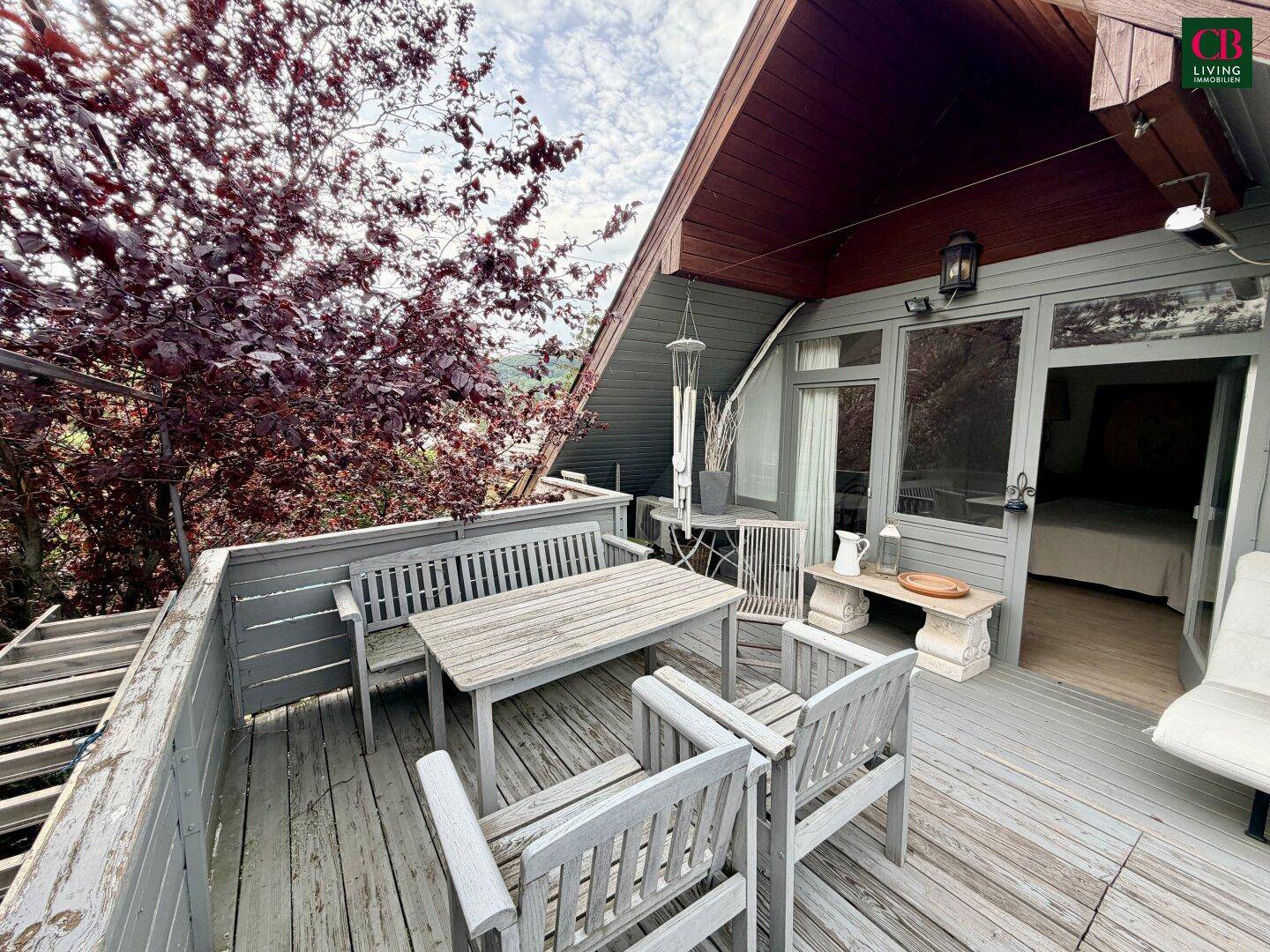 Geräumiger Balkon mit Holzboden, Sitzgelegenheiten und Blick ins Grüne, ideal zum Entspannen.