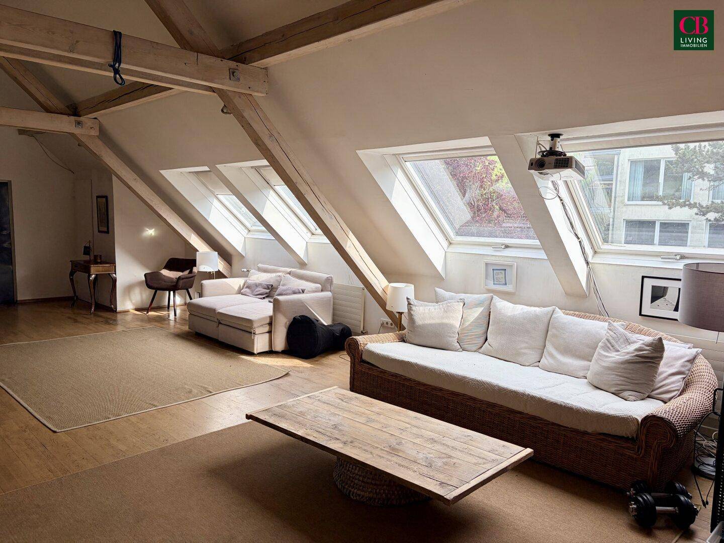 Helles Wohnzimmer im Dachgeschoss mit großen Dachfenstern, Holzboden und gemütlichen Sofas.