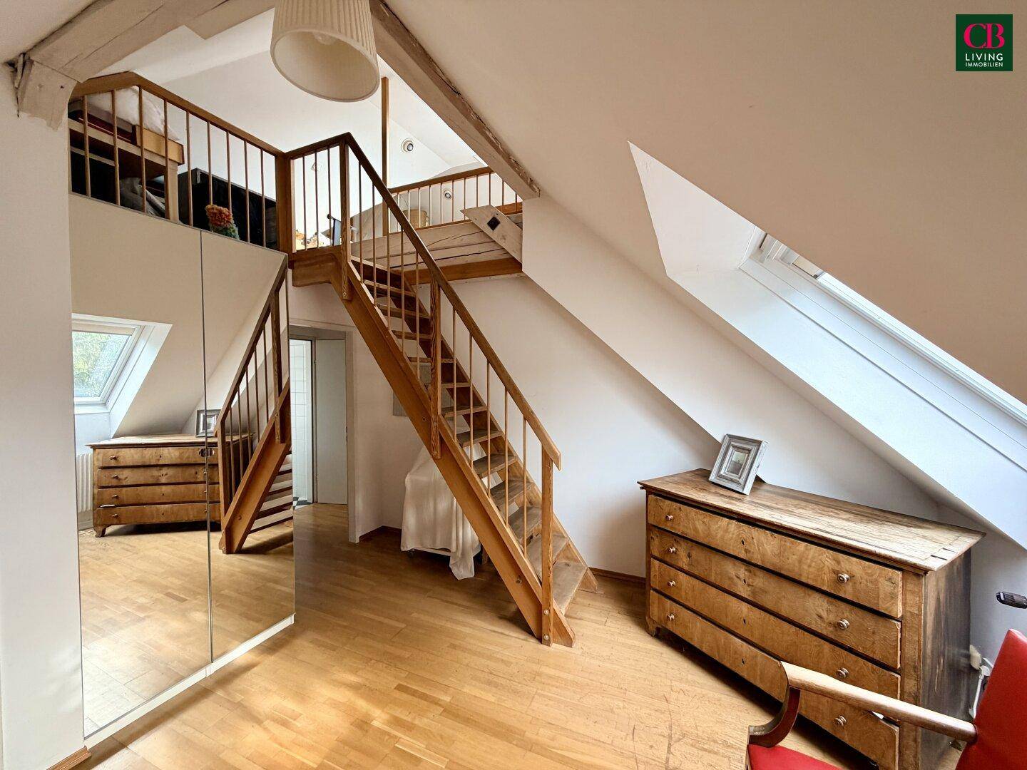 Schlafzimmer oder Flur im Dachgeschoss mit Holztreppe, Spiegelschränken und Holzboden.