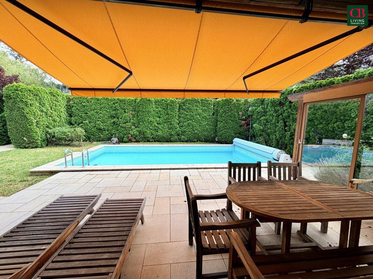 Sonnenterrasse mit Esstisch, Liegestühlen und Pool, geschützt durch eine große Markise.