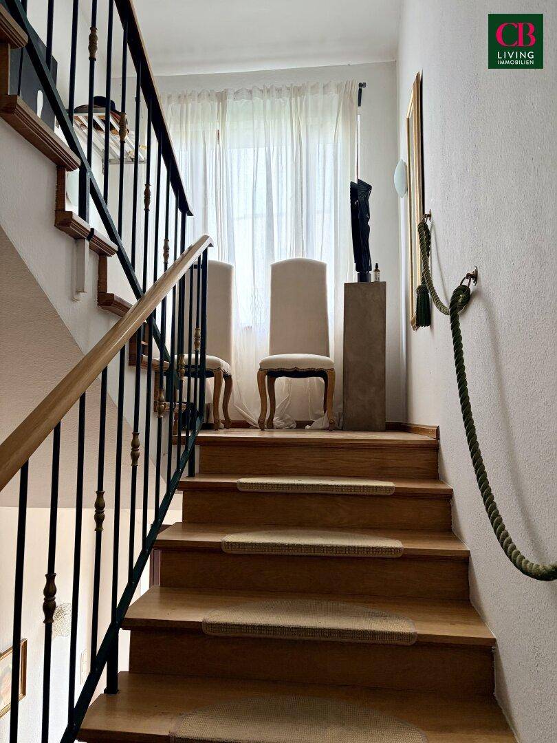 Treppenhaus mit Holzstufen, schmiedeeisernem Geländer und einem Seil als Handlauf.