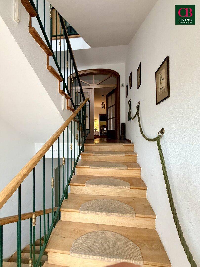 Traditionelles Treppenhaus mit Holzstufen, Teppichläufern und einem schmiedeeisernen Geländer.