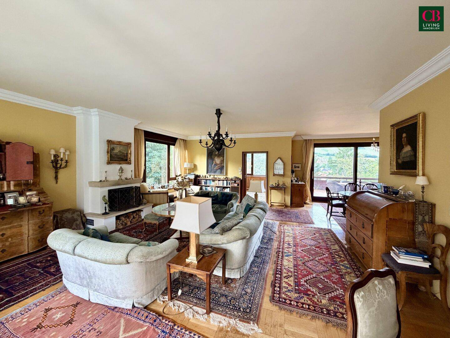 Elegantes Wohnzimmer mit Parkettboden, Kamin und Blick ins Grüne, klassisch eingerichtet.