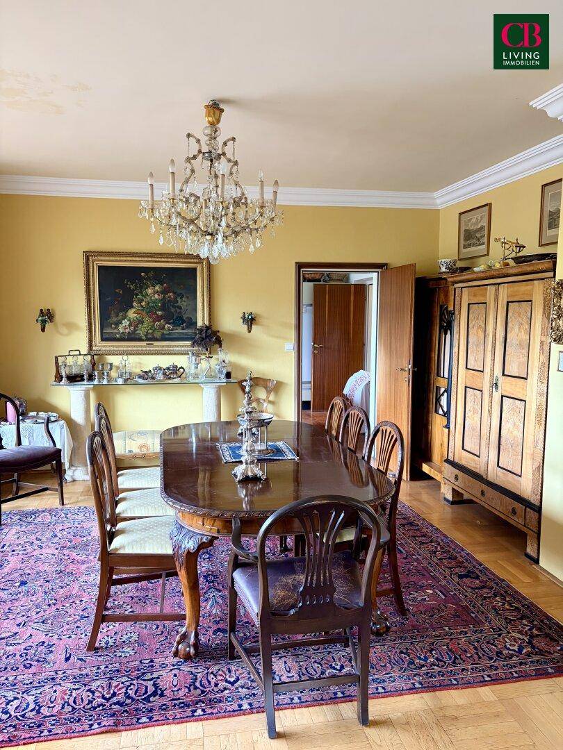 Klassisches Esszimmer mit großem Holztisch, Kronleuchter und Parkettboden, elegant gestaltet.