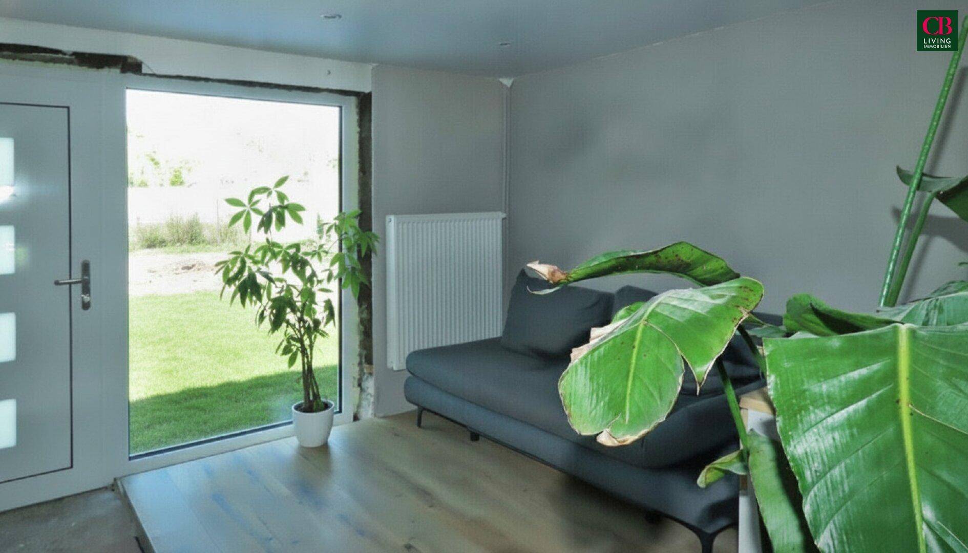 Heller Raum mit Zugang zum Garten und einer modernen Couch.