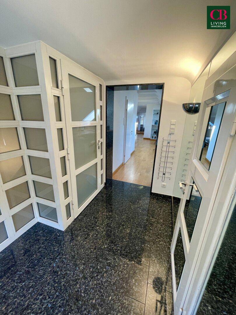 Heller Eingangsbereich mit Granitboden und modernen Glastüren, die in den Wohnbereich führen.