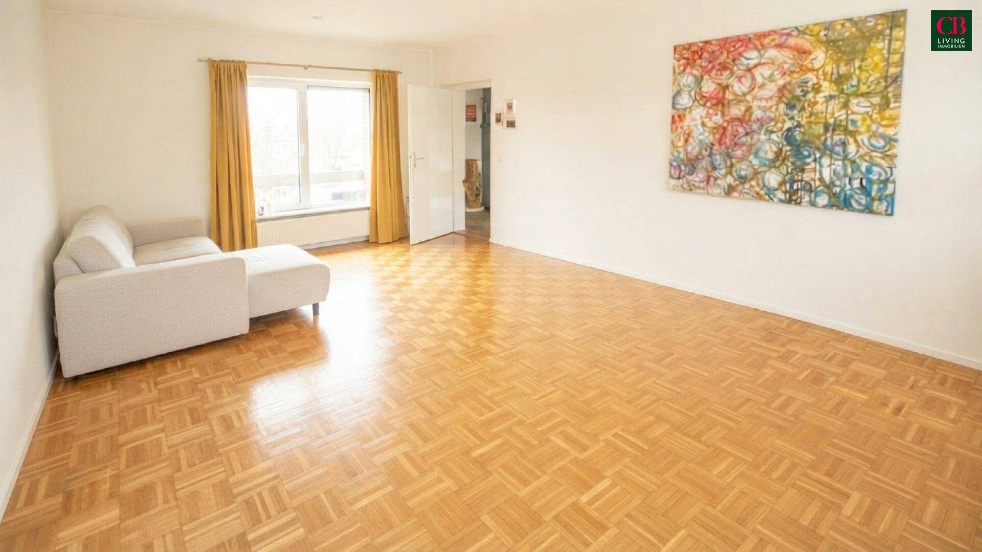 Geräumiges Wohnzimmer mit Parkettboden, einem bequemen Sofa und farbenfroher Wandkunst.