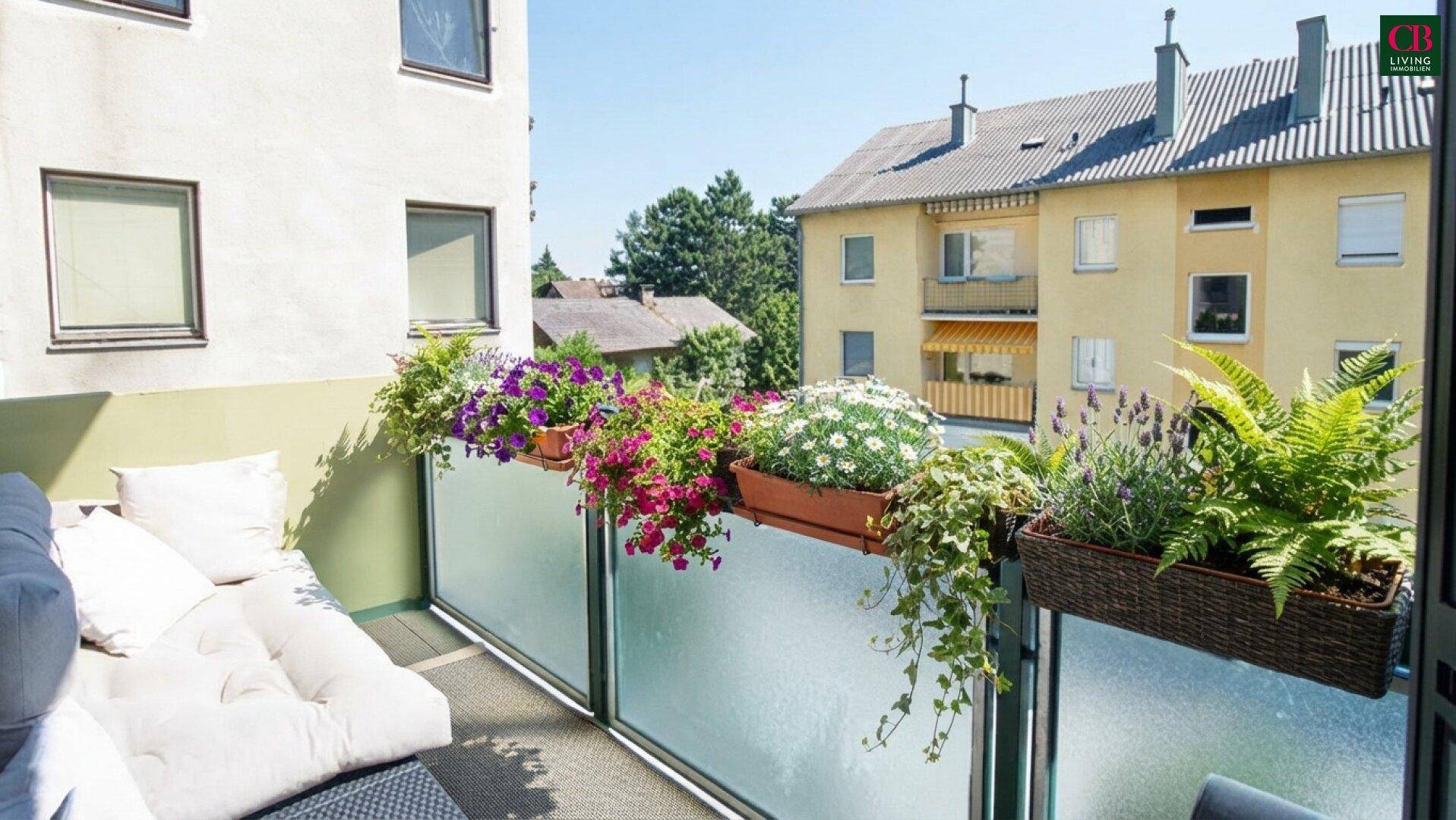 Heller Balkon mit bequemen Sitzgelegenheiten und vielen Blumenkästen, mit Blick auf die Umgebung.