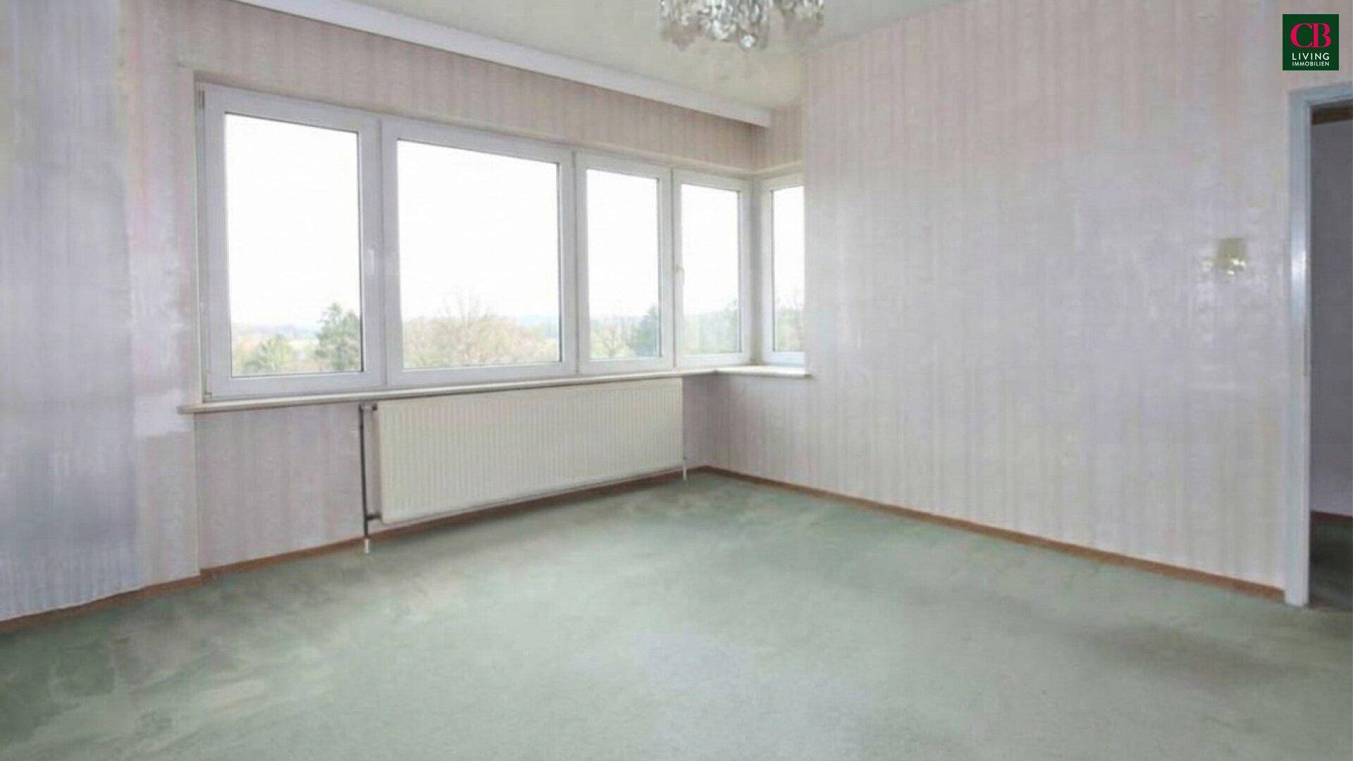 Geräumiges Zimmer mit Teppichboden, Eckfenstern und heller Tapete.