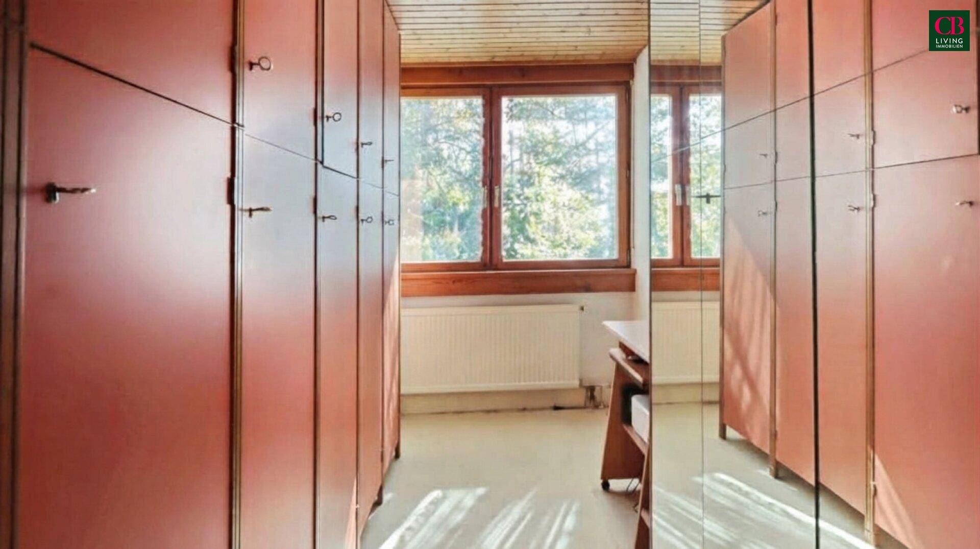 Flur mit eingebauten Holzschränken und einem Fenster am Ende, das Tageslicht hereinlässt.