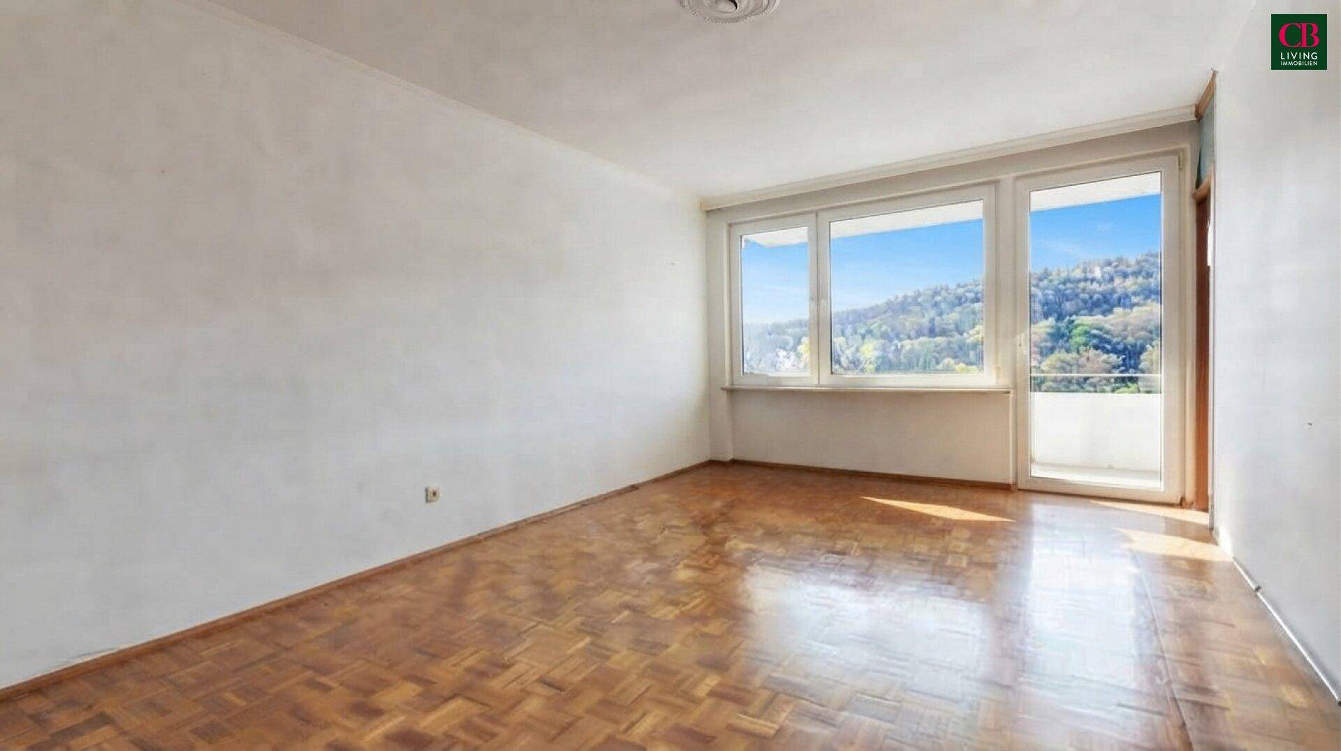 Geräumiges Zimmer mit Parkettboden und großen Fenstern, die einen weiten Blick auf die Landschaft bieten.
