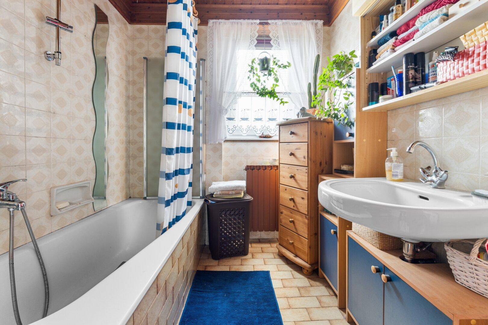 Badezimmer mit Badewanne, Waschbecken und Fenster, ausgestattet im traditionellen Stil.