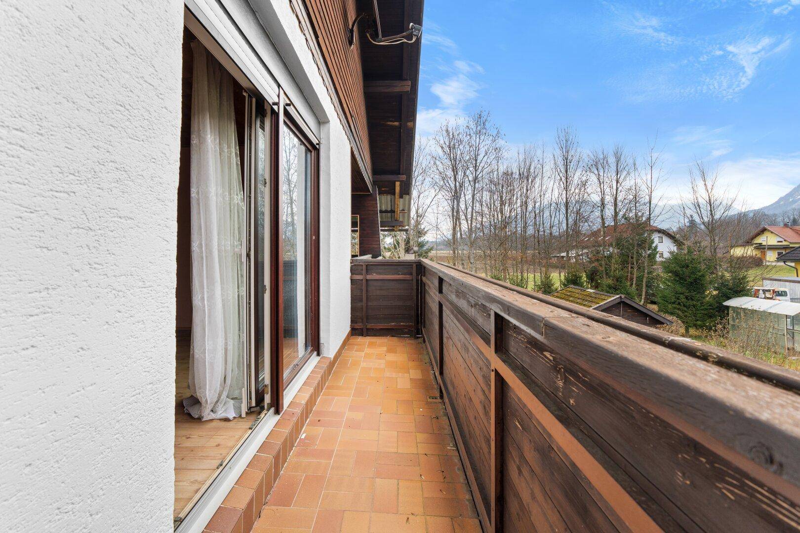 Langer Balkon mit Fliesenboden und Holzbalken, bietet Zugang zu frischer Luft.