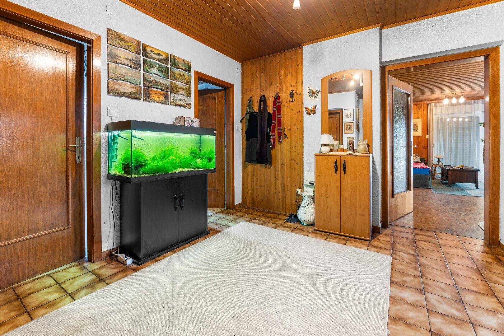 Flur mit Aquarium, Holzvertäfelung und Fliesenboden, verbindet verschiedene Räume.