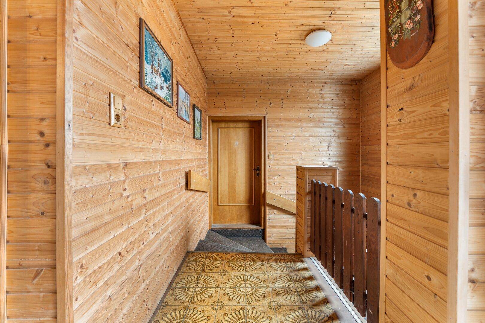 Flur und Treppenbereich mit Holzvertäfelung und gemustertem Teppichboden.