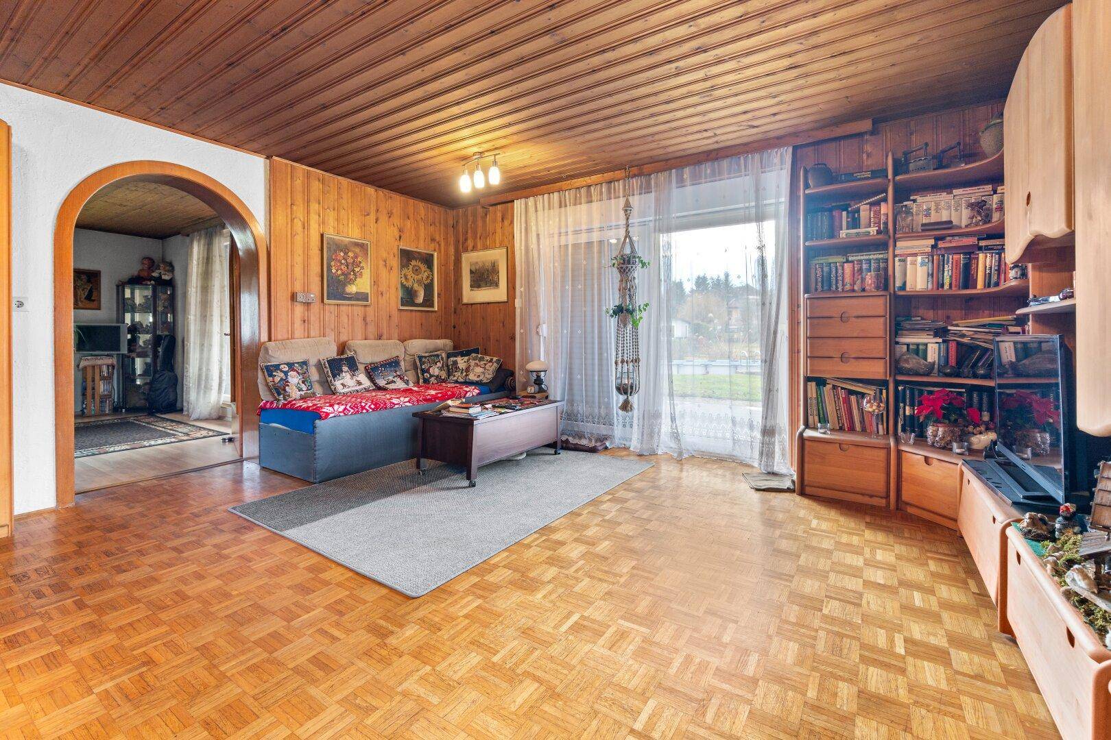 Wohnzimmer mit Parkettboden, Holzdecke und gemütlichem Sofa, ideal zum Entspannen.