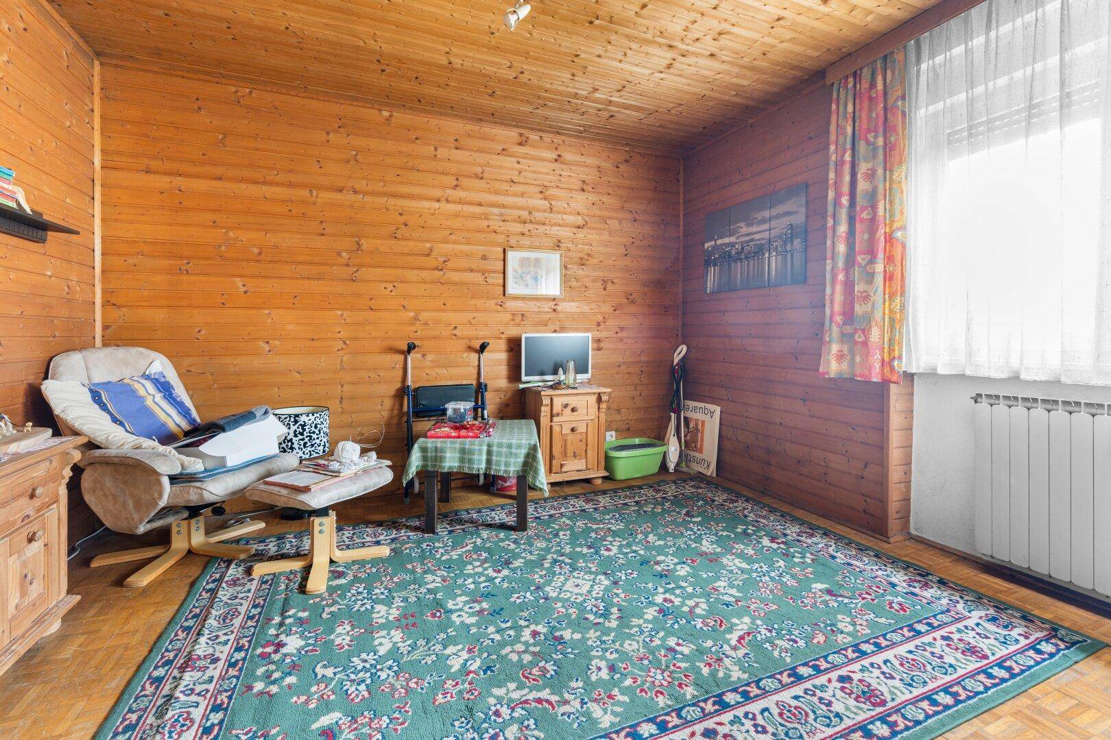 Raum mit Holzvertäfelung, Holzdecke und Teppichboden, bietet eine gemütliche Atmosphäre.