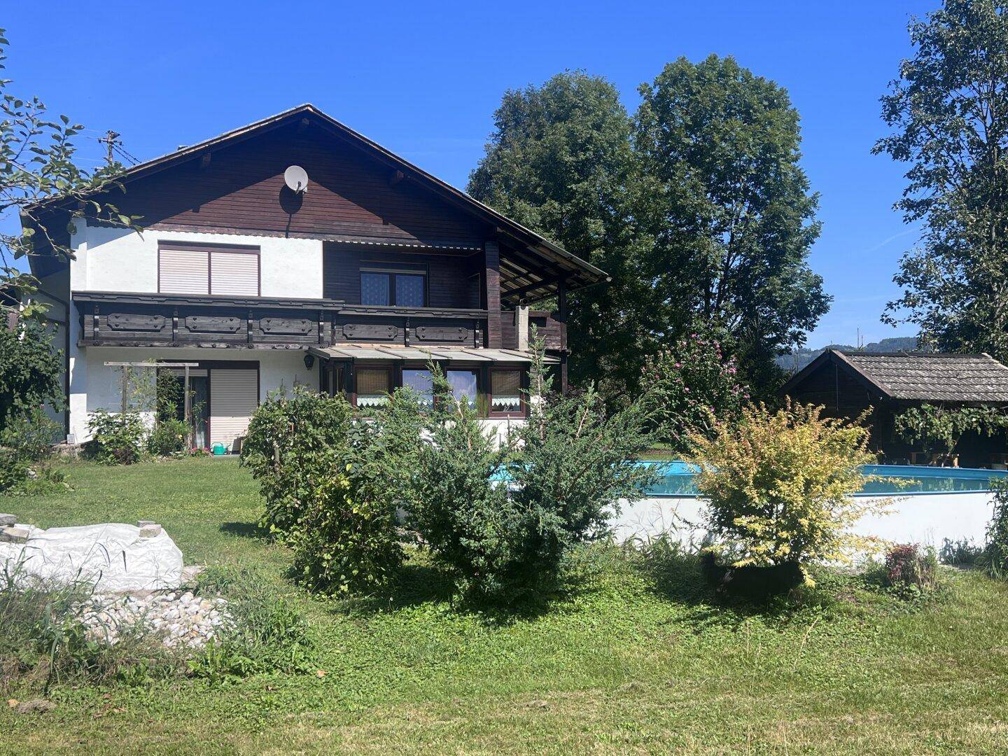 Rückansicht des Hauses mit Garten, kleinem Pool und üppiger grüner Vegetation.
