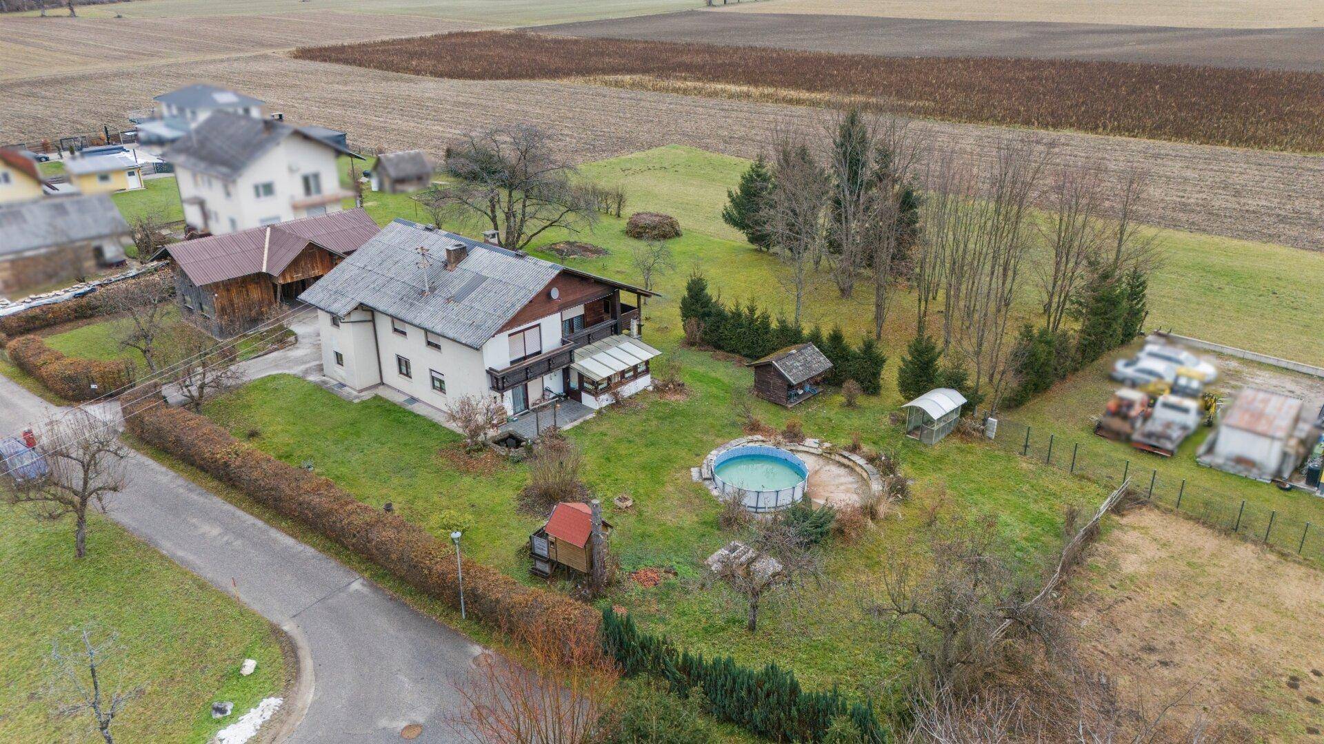 Luftaufnahme des Anwesens mit Wohnhaus, Pool, Garten und umliegenden Feldern.