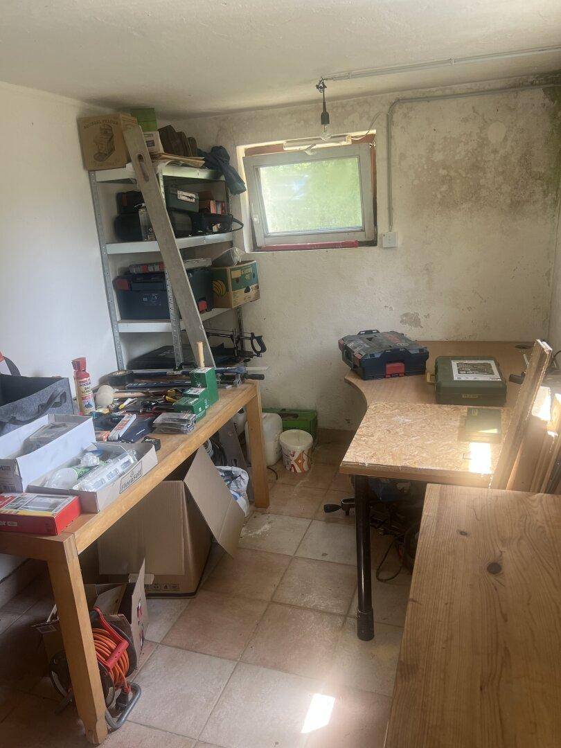 Werkstatt oder Abstellraum mit Regalen, Werkzeugen und einem Fenster für Tageslicht.