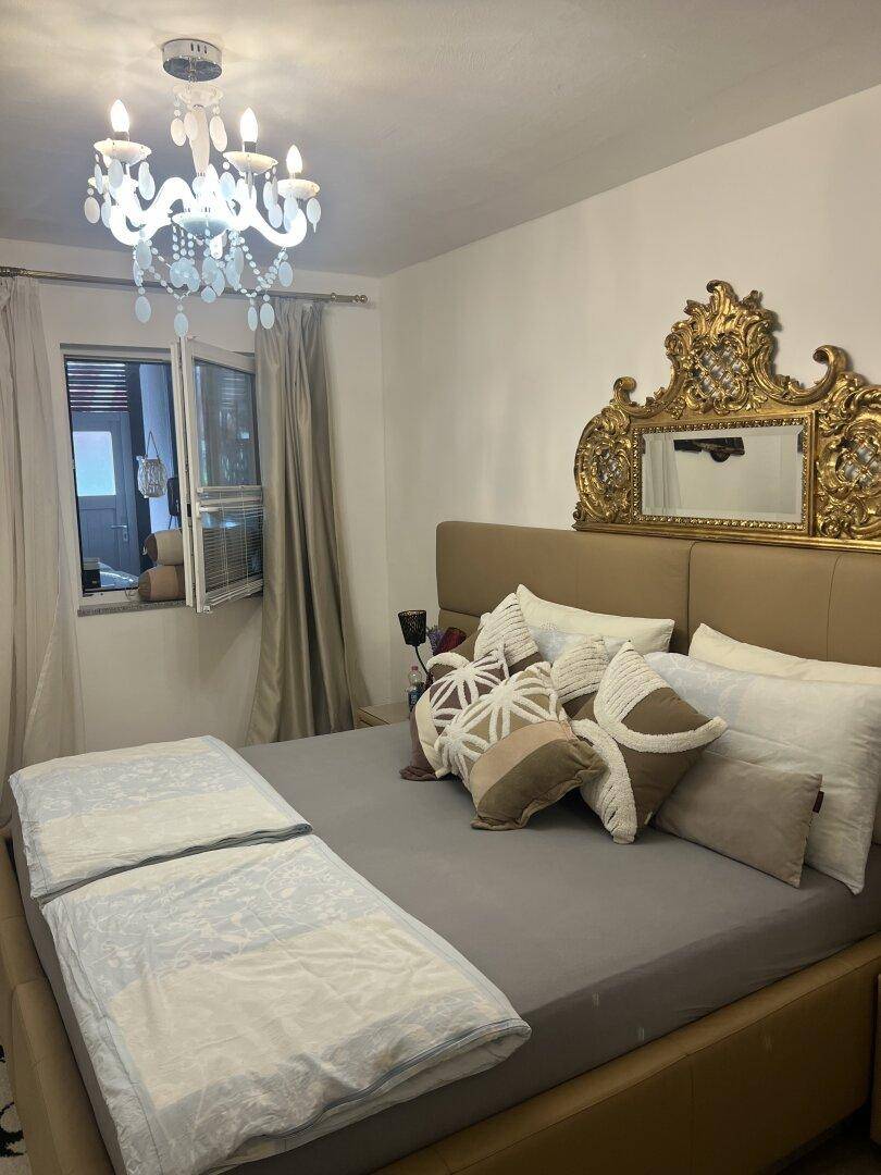 Gemütliches Schlafzimmer mit großem Bett, opulentem Spiegelkopfteil und elegantem Kronleuchter.