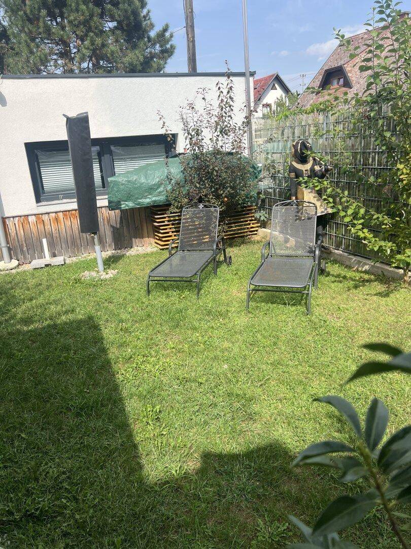 Grüner Garten mit Rasenfläche und zwei Sonnenliegen, ideal zum Entspannen im Freien.