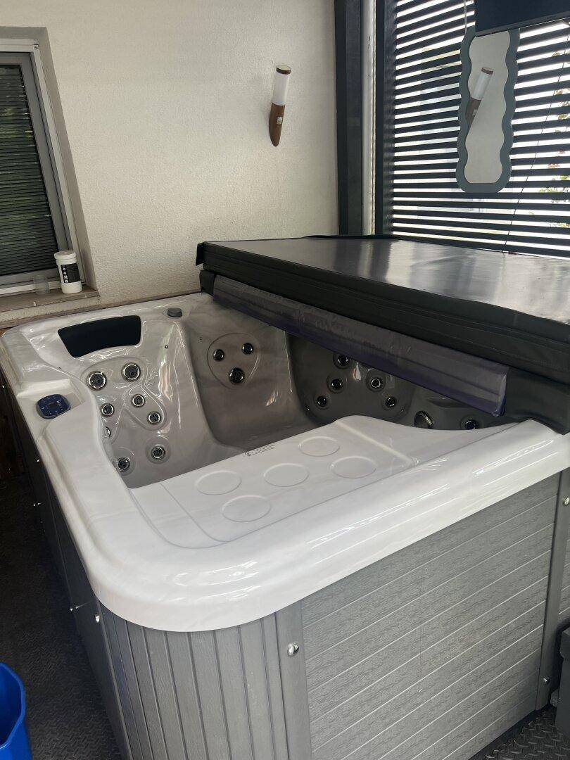 Moderner Whirlpool mit Abdeckung, bereit zur Nutzung im Außenbereich auf einer Terrasse.