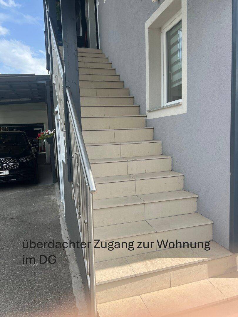 Außentreppe mit Fliesenstufen und Edelstahlgeländer, die zum Dachgeschoss führt.