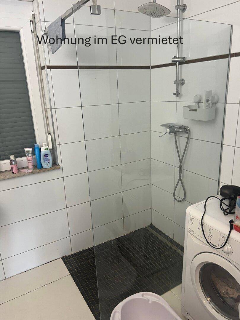 Badezimmer in einer Erdgeschosswohnung mit begehbarer Dusche und Waschmaschine.