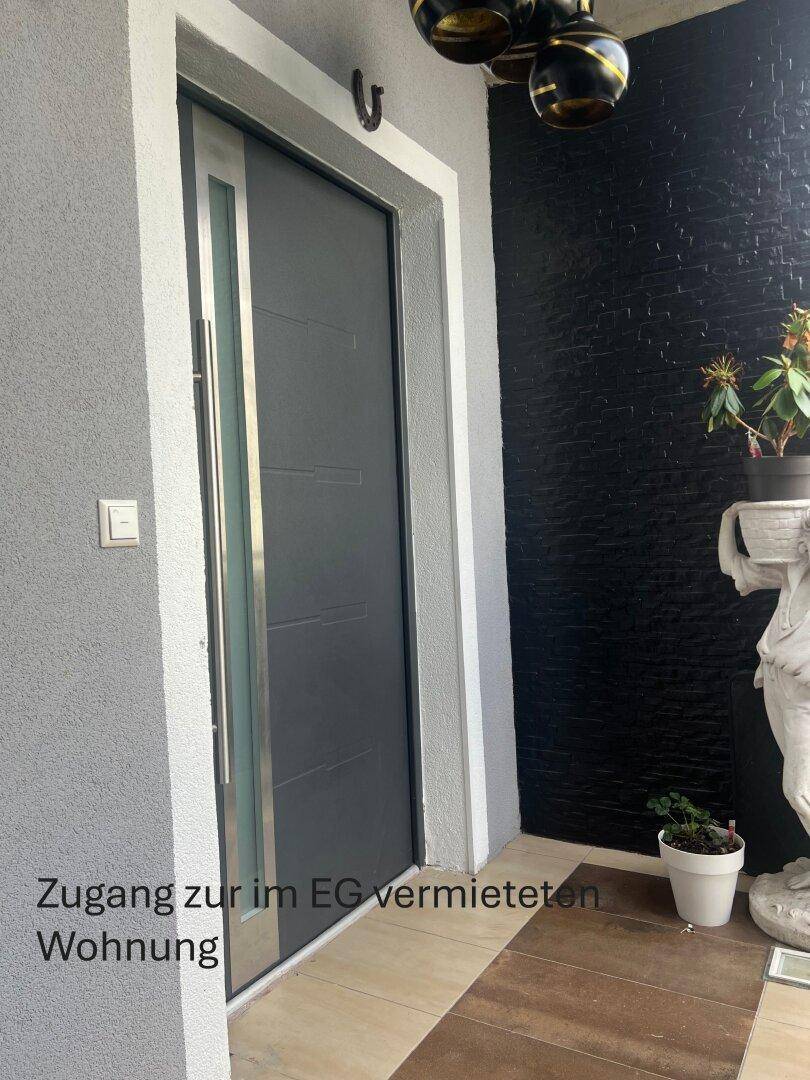 Eingangstür zu einer Erdgeschosswohnung mit moderner Gestaltung und dunkler Akzentwand.