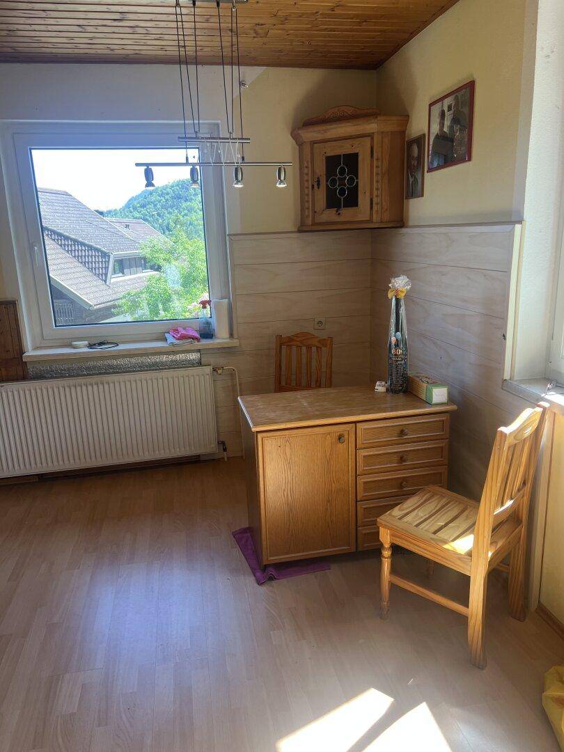 Heller Raum mit Holzdecke, Parkettboden und einem Schreibtisch am Fenster.