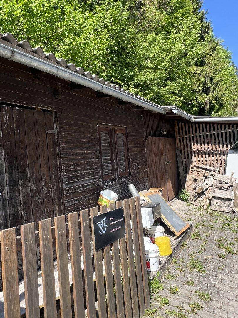 Rustikaler Holzschuppen mit Wellblechdach und gelagertem Material im Freien.