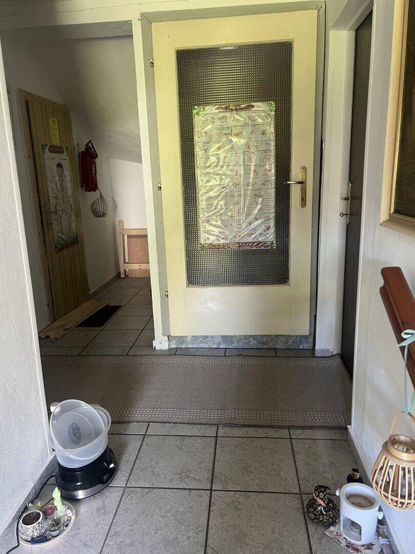 Heller Flur mit Fliesenboden und einer Tür mit Glaseinsatz, typisch für ältere Bauweise.